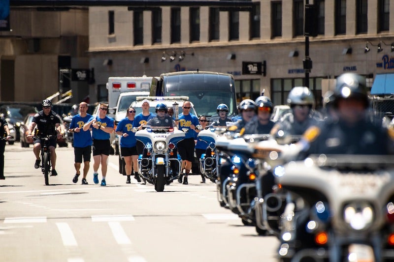 Pitt Police officers running up Forbes avenue with Police escort