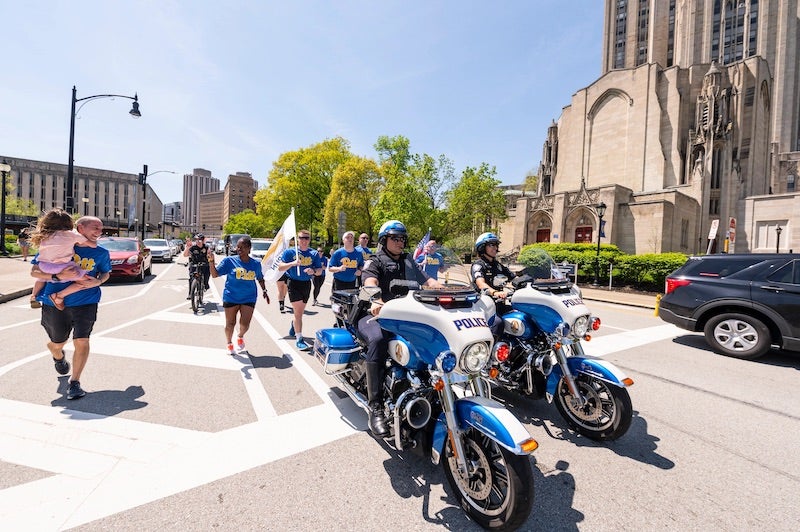 Pitt Police officers running up Forbes avenue with Police escort