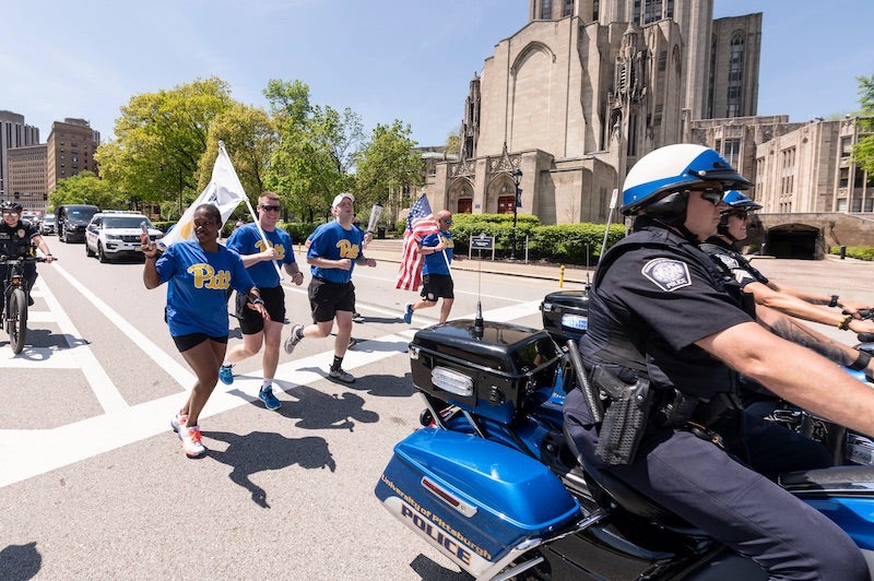 Pitt Police officers running up Forbes avenue with Police escort