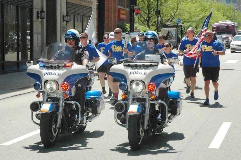 Pitt Police officers running up Forbes avenue with Police escort