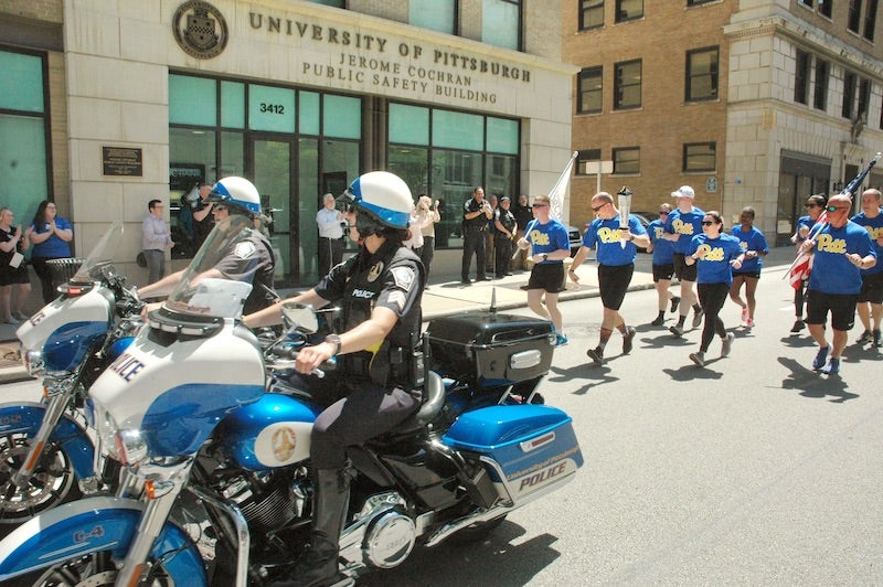 Pitt Police officers running up Forbes avenue with Police escort