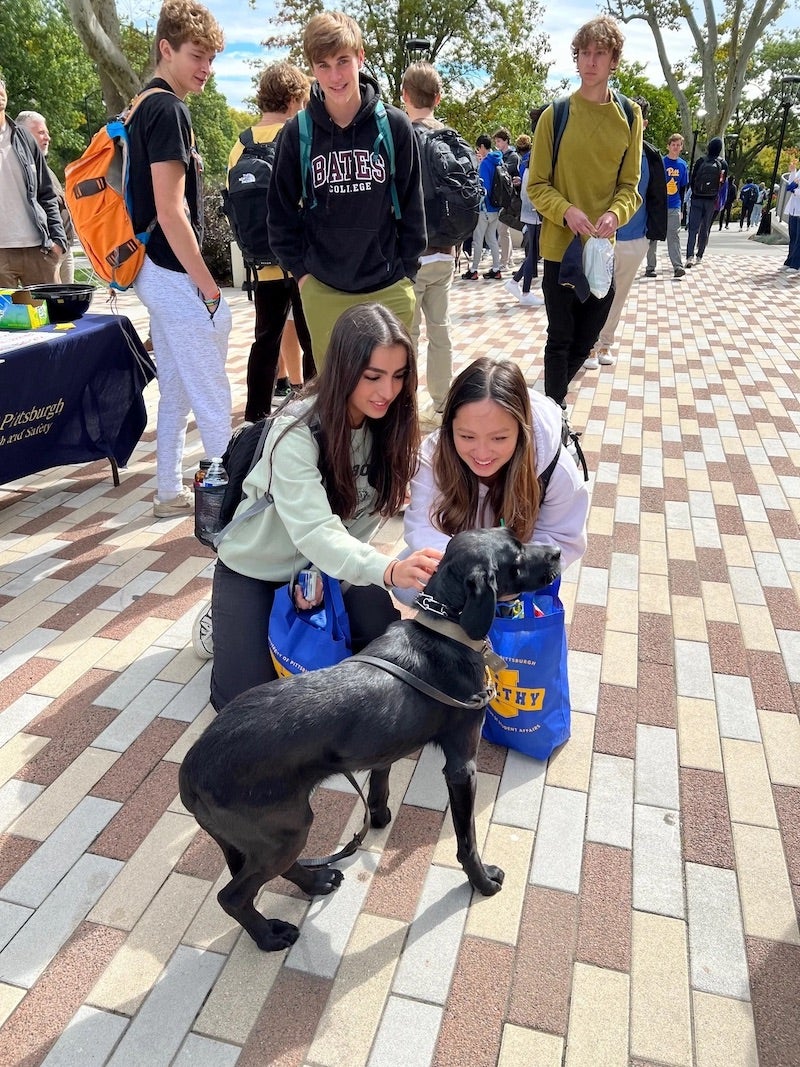 two student petting a dog