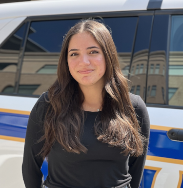 Lauren Alamo, Pitt Police intern, standing in front of police vehicle.