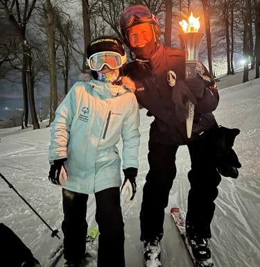 Special Olympics athlete and Sgt. Urban on skis holding the SOPA torch