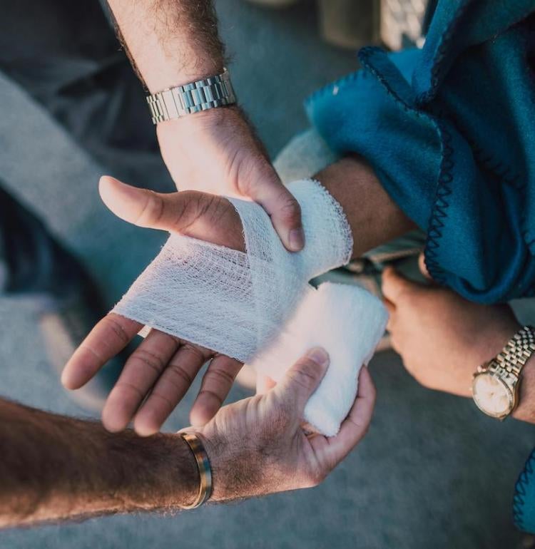 person getting their hand bandaged